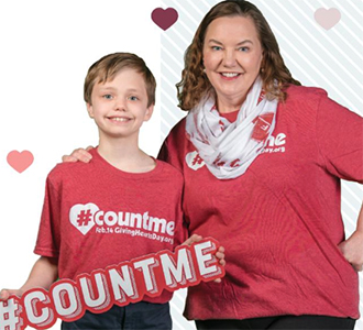 a young boy and his mom holding a #countme sign and smiling at the camera